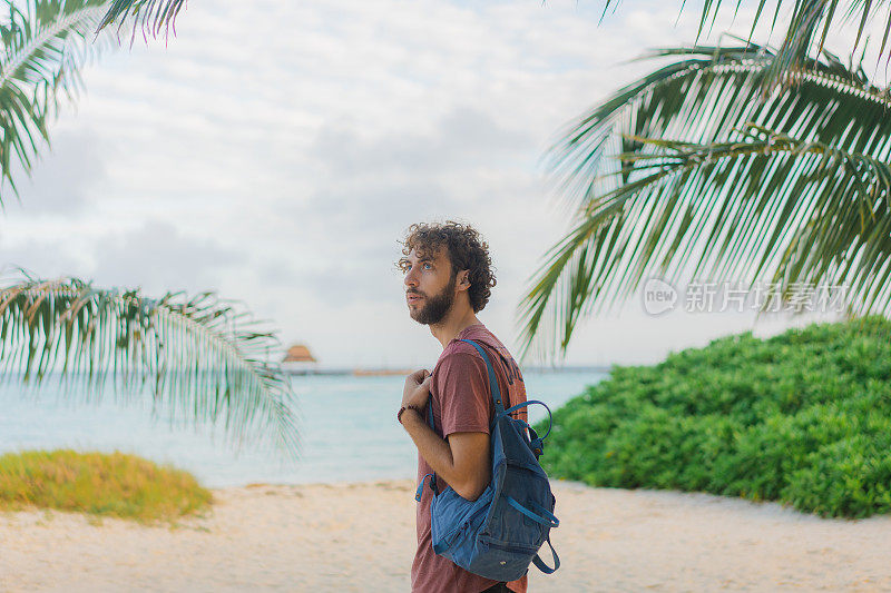 男子背着背包走在Isla Mujeres海滩的海边